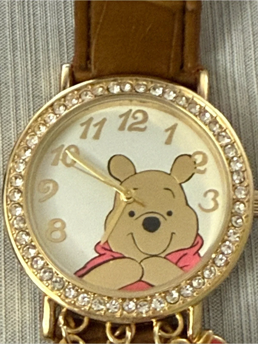 Disney Winnie the Pooh watch features a crystal-bezel dial and dangling charms o